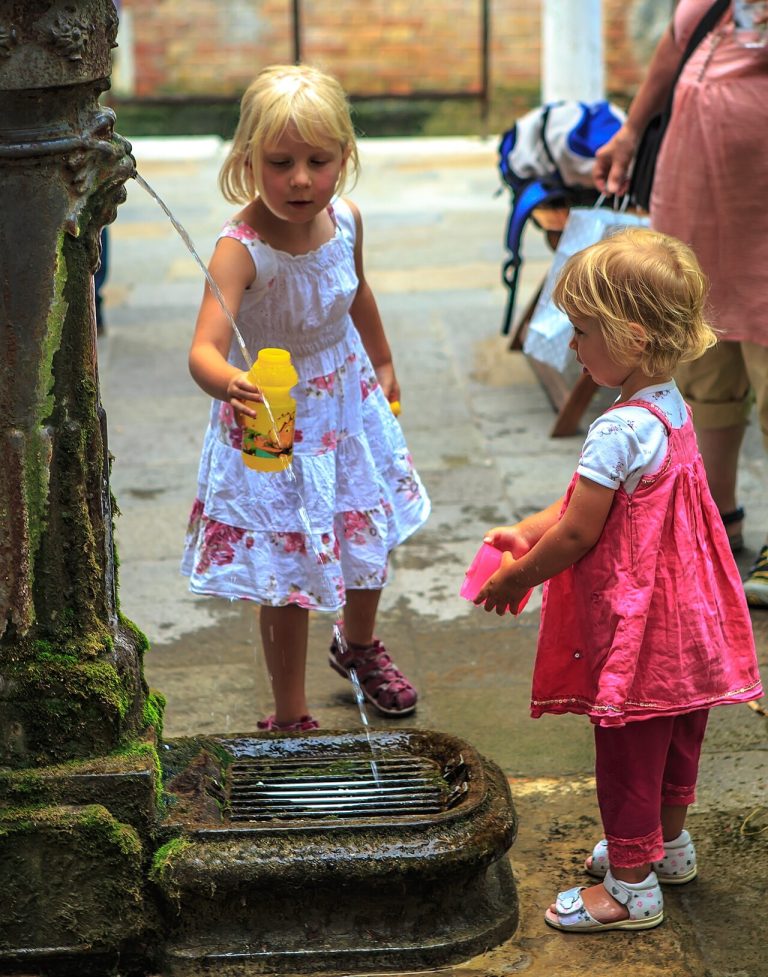 Children cooling off at a drinking fountain in Venice on a summer day