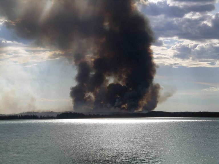 Wildfire Smoke Seasons Are Getting Longer, Agencies Warn Smoke rising from a forest wildfire under a hazy sky